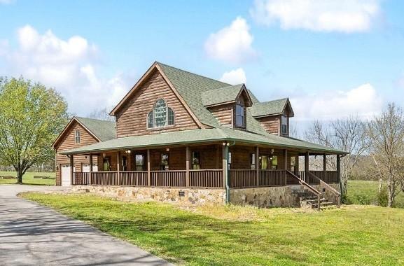 country-style home with a front yard, a porch, and a garage