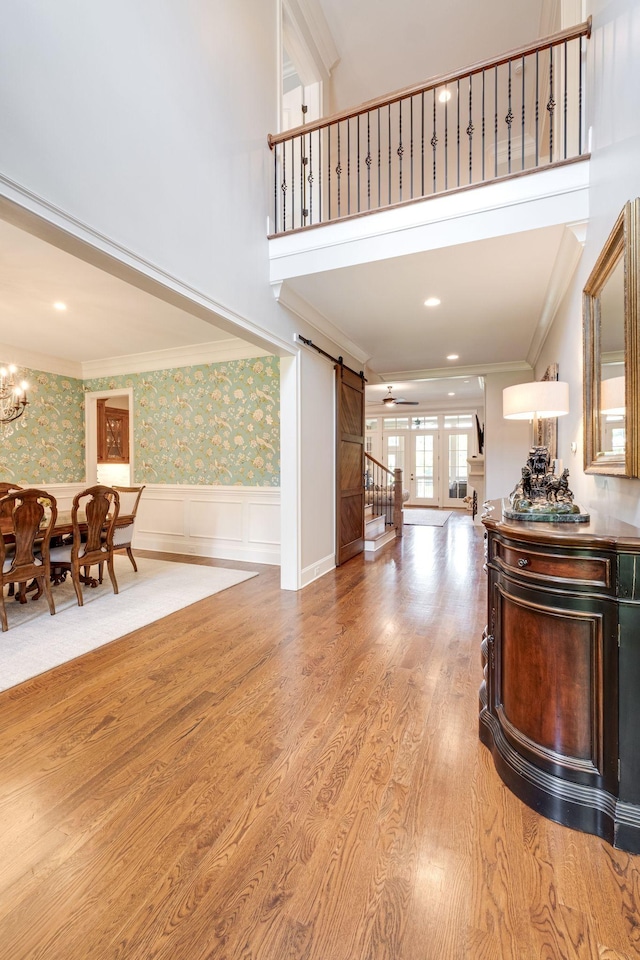 foyer entrance featuring a barn door, light wood-type flooring, and ornamental molding