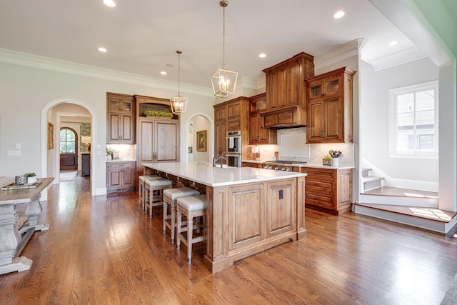 kitchen with pendant lighting, a large island, ornamental molding, and appliances with stainless steel finishes