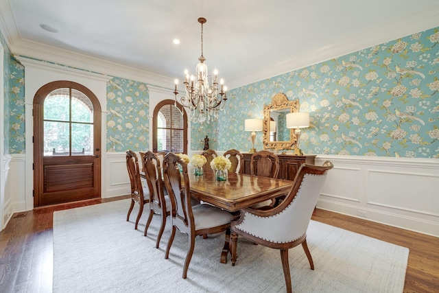 dining area with hardwood / wood-style floors, ornamental molding, and a chandelier