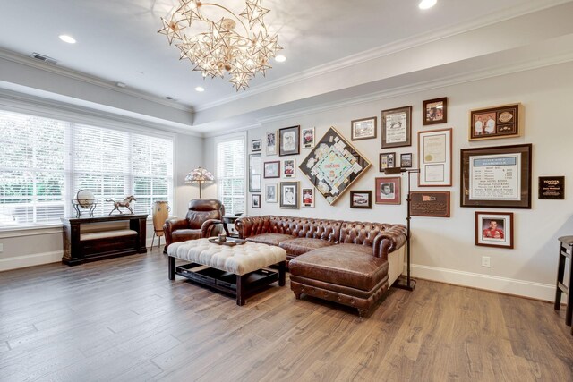 living room with crown molding, hardwood / wood-style floors, and a notable chandelier