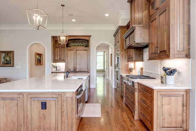 kitchen with pendant lighting, stainless steel gas stovetop, ornamental molding, tasteful backsplash, and a large island