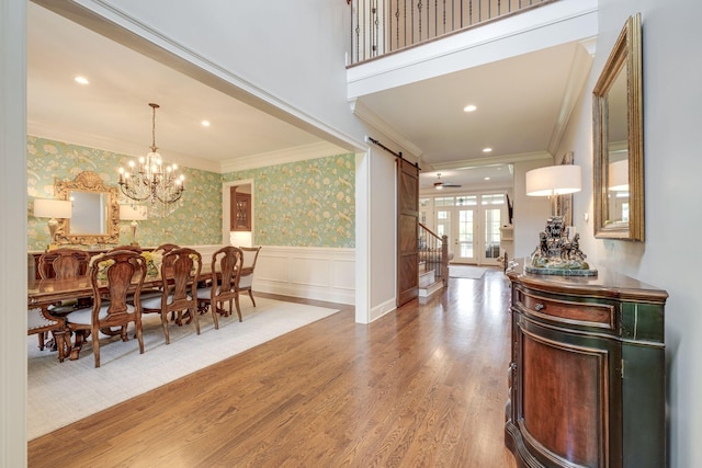 dining area featuring a chandelier, a barn door, hardwood / wood-style flooring, and crown molding