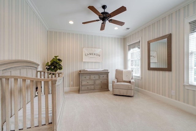 carpeted bedroom with ceiling fan, a nursery area, and ornamental molding