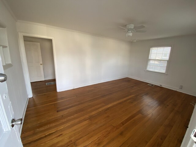 empty room with ceiling fan, ornamental molding, and dark wood-type flooring