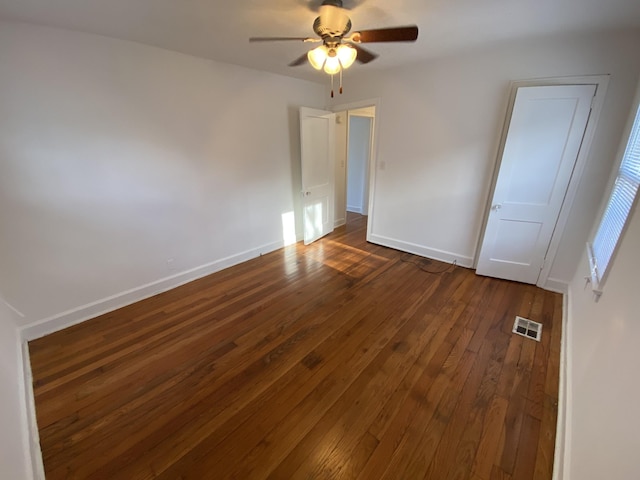 unfurnished bedroom featuring a ceiling fan, visible vents, dark wood finished floors, and baseboards