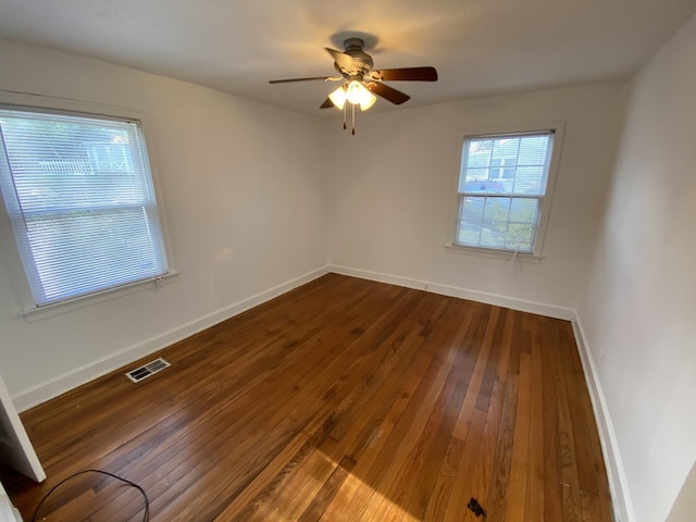 spare room with baseboards, visible vents, ceiling fan, and dark wood-type flooring