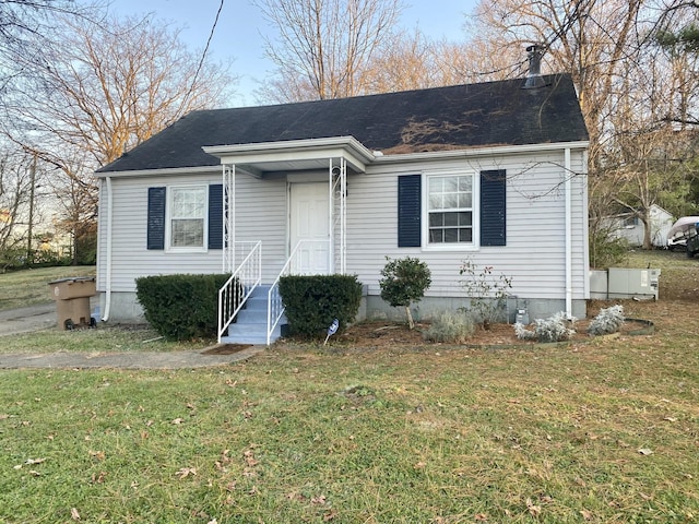 view of front facade with roof with shingles and a front yard