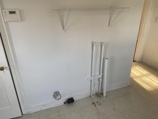 clothes washing area with light tile patterned floors and baseboards