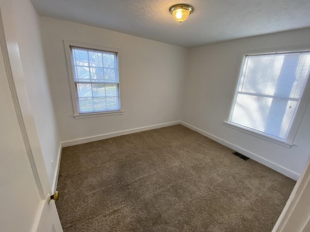 carpeted empty room featuring baseboards, visible vents, and a textured ceiling