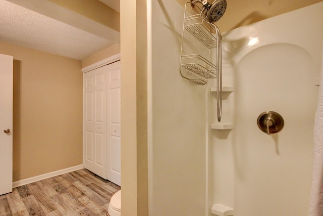 bathroom with hardwood / wood-style floors, toilet, a shower, and a textured ceiling