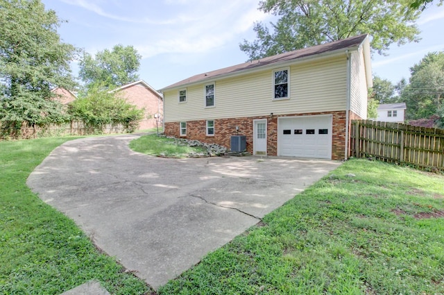 rear view of house featuring central AC, a yard, and a garage