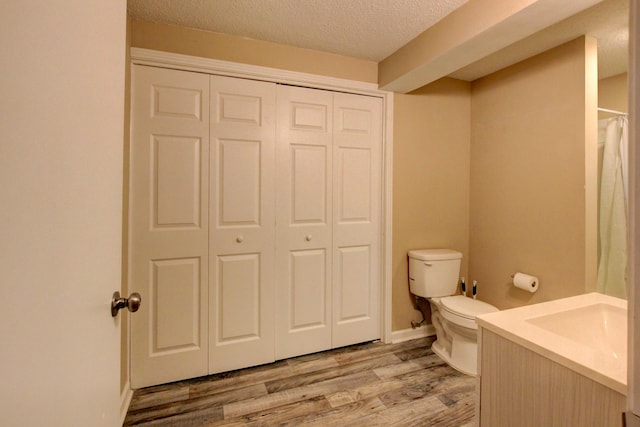 bathroom with vanity, wood-type flooring, a textured ceiling, and toilet