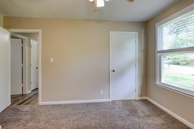 spare room with dark carpet, ceiling fan, and a healthy amount of sunlight