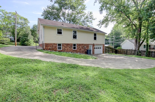 view of side of property with a lawn, central air condition unit, and a garage