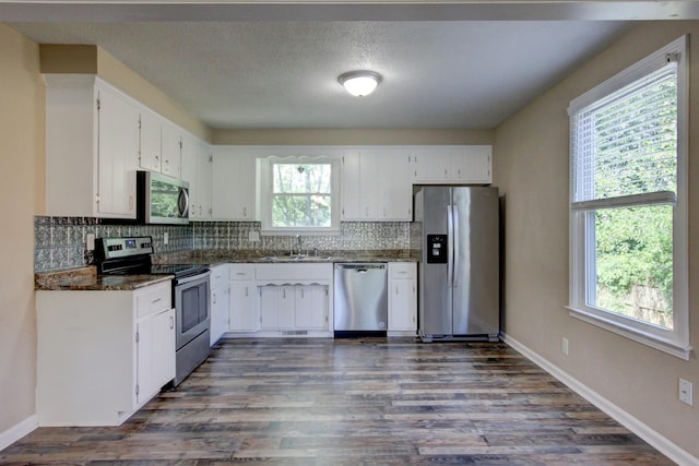 kitchen featuring white cabinets, appliances with stainless steel finishes, dark stone counters, and sink