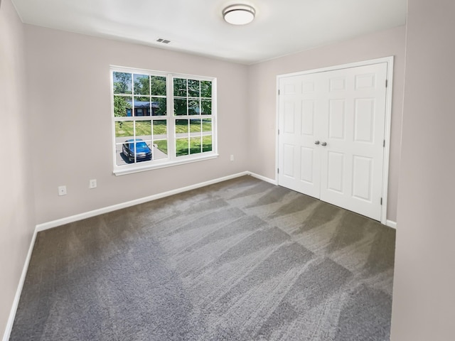 unfurnished bedroom featuring dark carpet and a closet