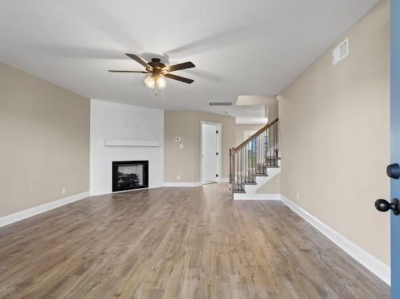 unfurnished living room with ceiling fan and hardwood / wood-style flooring