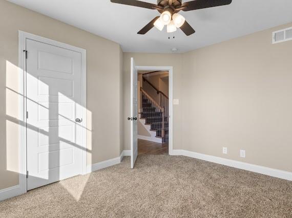 carpeted empty room featuring ceiling fan