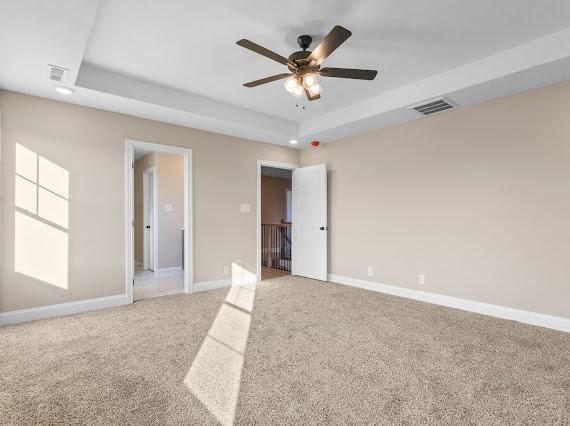 unfurnished bedroom featuring carpet floors, ceiling fan, and a tray ceiling