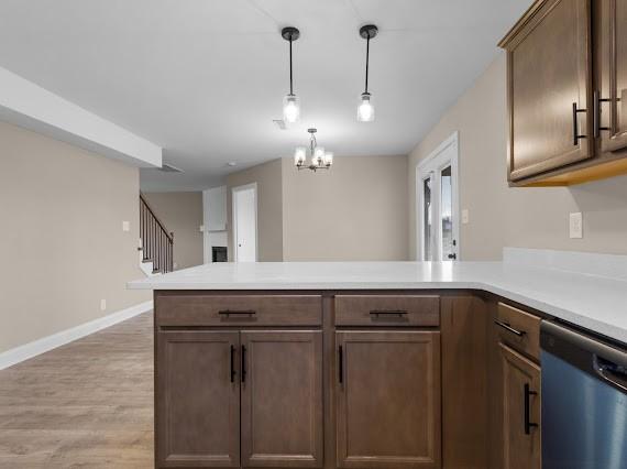 kitchen featuring stainless steel dishwasher, an inviting chandelier, pendant lighting, and kitchen peninsula