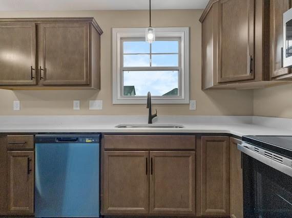 kitchen featuring sink, decorative light fixtures, electric stove, and dishwashing machine