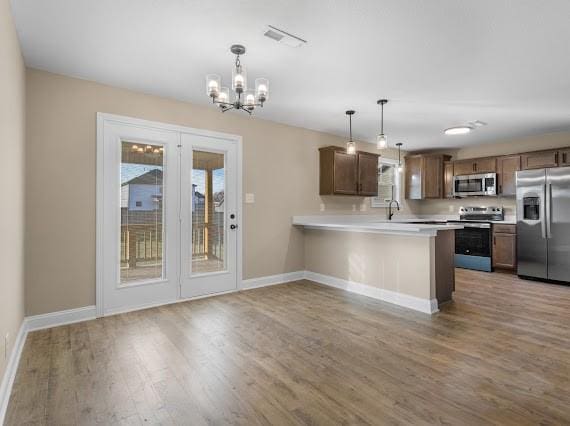 kitchen featuring kitchen peninsula, an inviting chandelier, appliances with stainless steel finishes, and hanging light fixtures