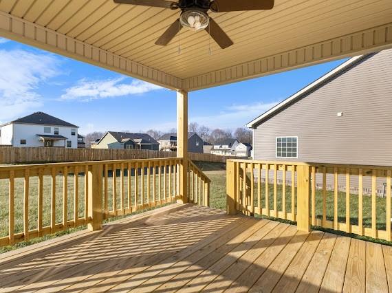 wooden terrace featuring ceiling fan and a yard