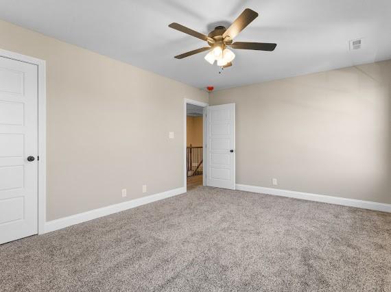 unfurnished room with ceiling fan and carpet