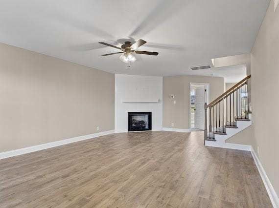 unfurnished living room with a large fireplace, ceiling fan, and light hardwood / wood-style floors