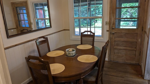 dining room with dark hardwood / wood-style floors and wooden walls