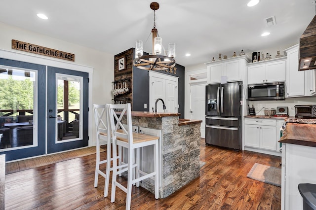 1033 Carter Rd SE, Old Fort, TN 37362 - kitchen featuring a breakfast bar area, white cabinets, dark hardwood / wood-style flooring, hanging light fixtures, and stainless steel appliances