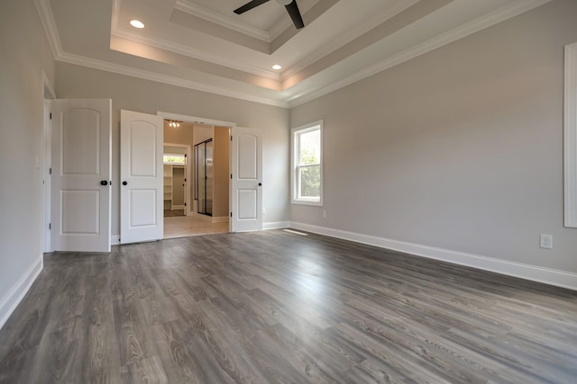 spare room with ceiling fan, dark hardwood / wood-style floors, ornamental molding, and a tray ceiling