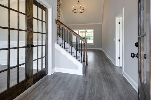 foyer entrance featuring french doors, dark hardwood / wood-style flooring, an inviting chandelier, and crown molding