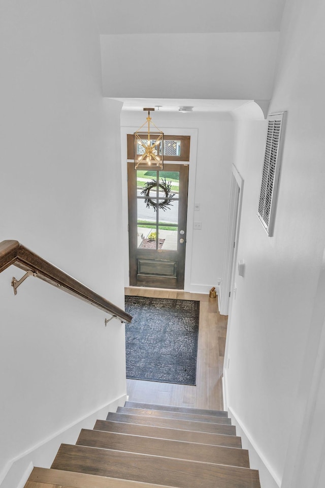 foyer entrance with hardwood / wood-style floors and a notable chandelier