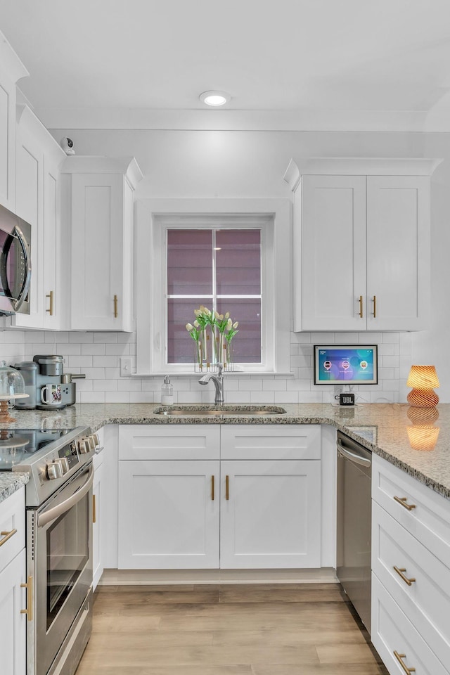 kitchen featuring white cabinetry, light stone counters, appliances with stainless steel finishes, and tasteful backsplash