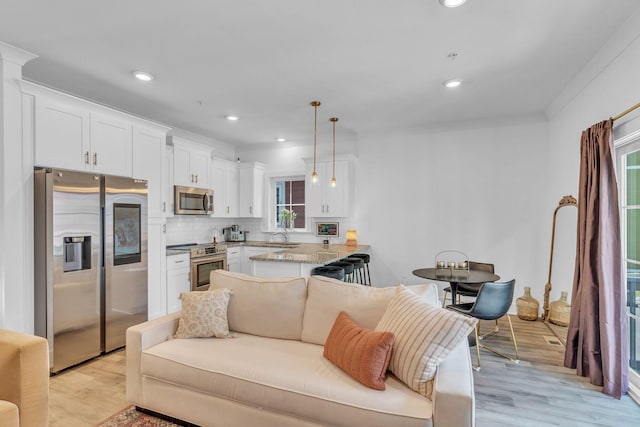 kitchen with pendant lighting, white cabinets, appliances with stainless steel finishes, tasteful backsplash, and kitchen peninsula