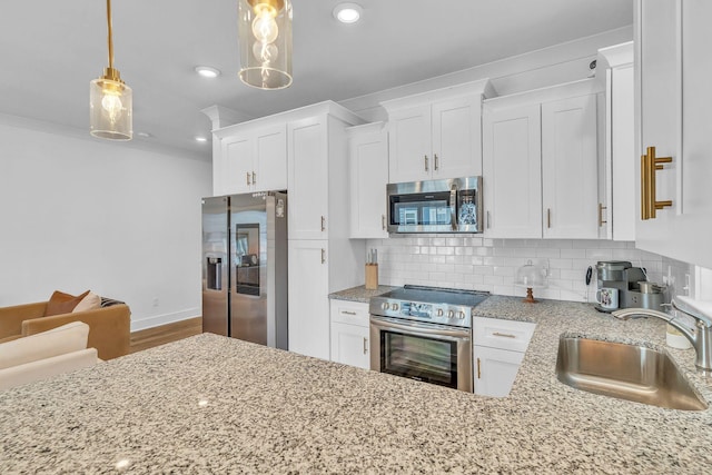 kitchen featuring white cabinetry, sink, hanging light fixtures, and appliances with stainless steel finishes