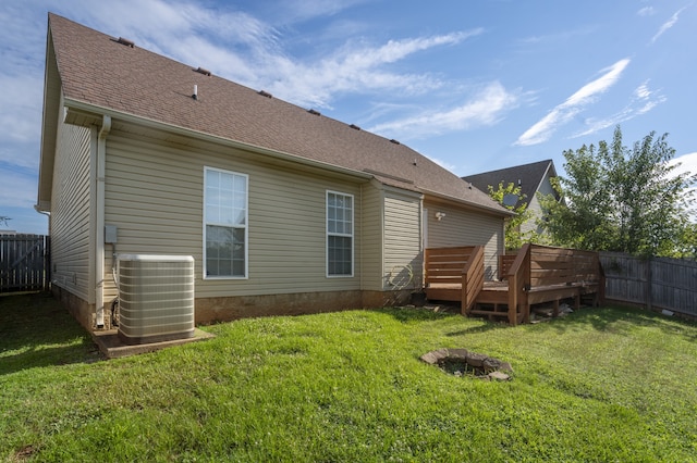 rear view of property with central air condition unit, a lawn, and a deck