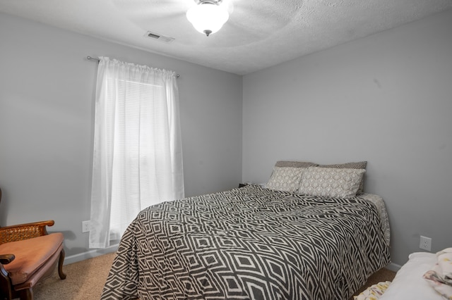 bedroom featuring a textured ceiling, ceiling fan, and carpet floors