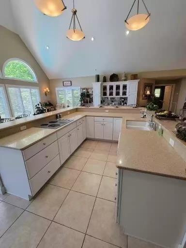 kitchen with decorative light fixtures, kitchen peninsula, sink, and white cabinets