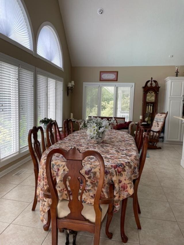 dining space featuring high vaulted ceiling and light tile patterned flooring