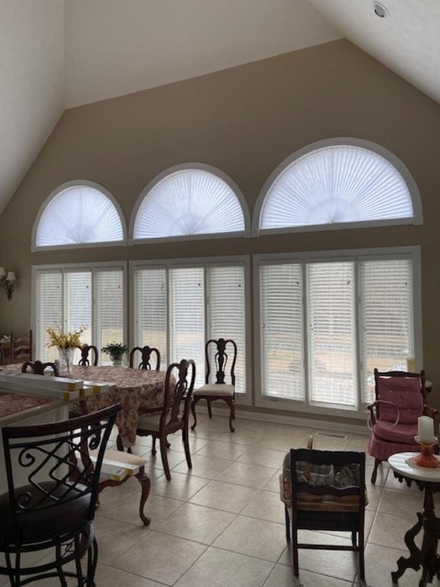 tiled dining room featuring high vaulted ceiling