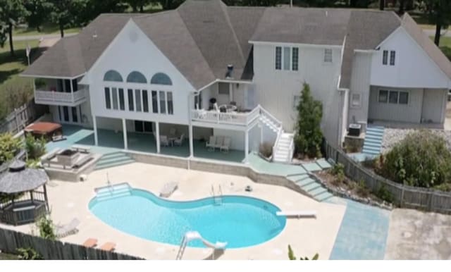 rear view of property featuring a fenced in pool, a patio, and a balcony