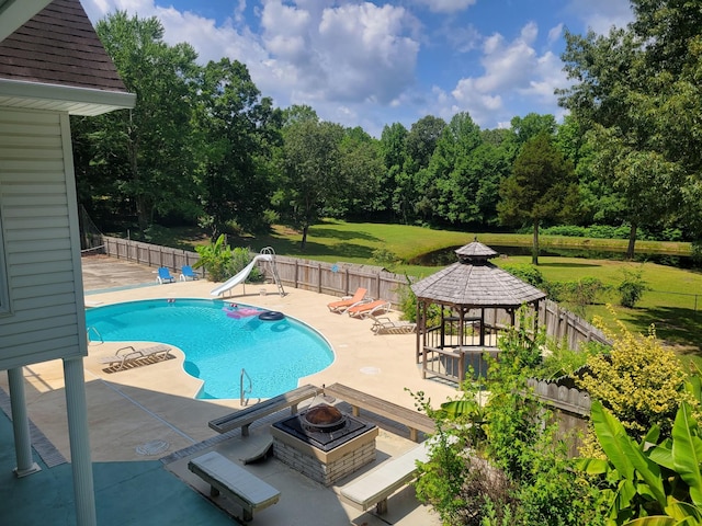 view of swimming pool with a fire pit, a water slide, a yard, a gazebo, and a patio area