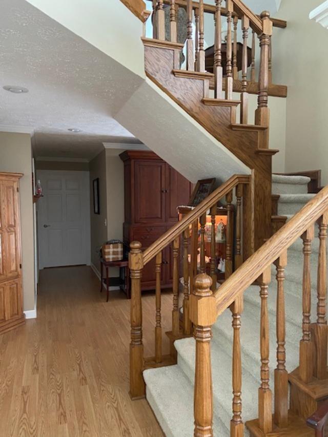 stairs featuring crown molding, hardwood / wood-style floors, and a textured ceiling