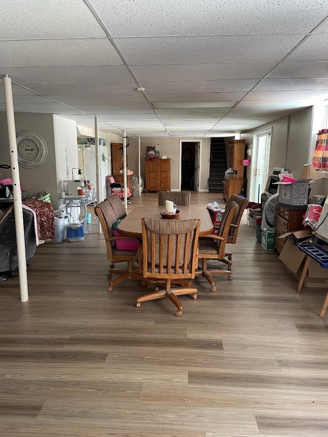 dining room featuring wood-type flooring and a drop ceiling