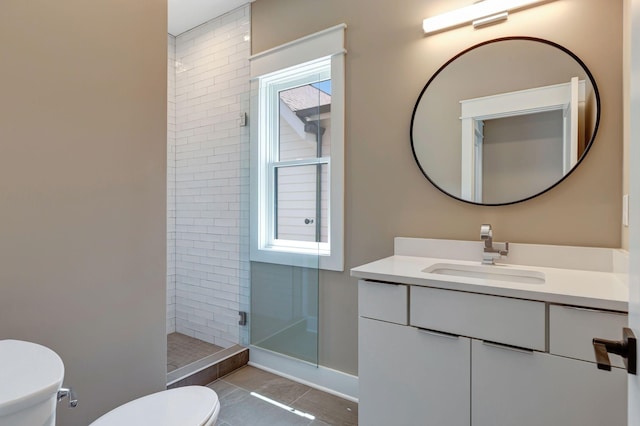 bathroom with tile patterned flooring, vanity, tiled shower, and toilet