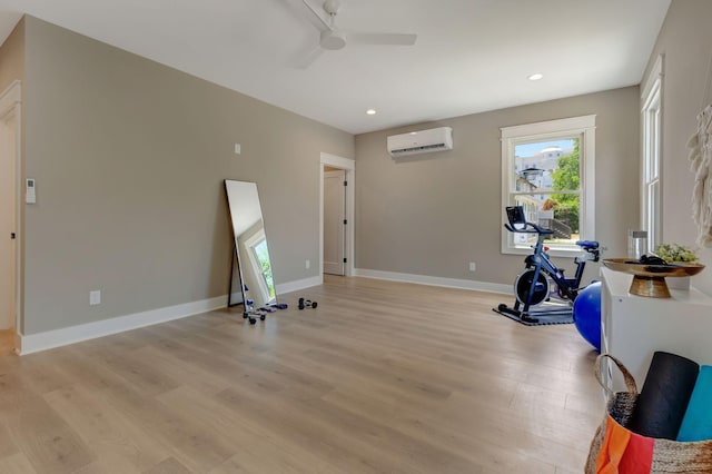 exercise area with a wall unit AC, ceiling fan, and light wood-type flooring