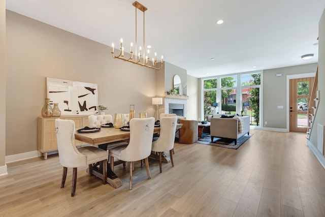 dining area featuring light wood finished floors, a fireplace, recessed lighting, and baseboards